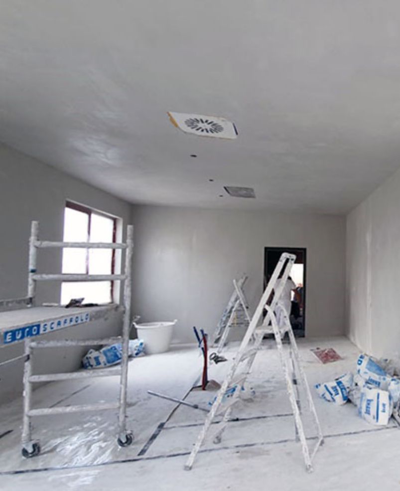 kamer met plastic op de vloer. Ladders en gereedschap verspreid door de kamer. Klaar om geschilderd te worden.